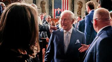 King Charles, with a grin on his face, walks by lawmakers in US Congress after delivering his speech, with US Vice-President JD Vance and a US flag visible distantly behind him