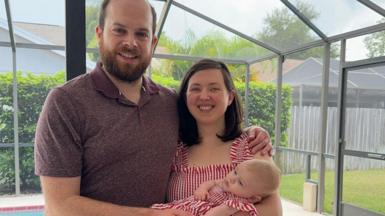 The Frost family at home in Tampa, Florida, a woman is holding her five month old baby, standing next to a man who is her husband