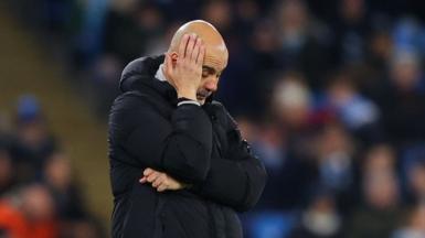 Pep Guardiola clasps his right hand to his head