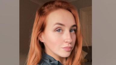 A woman with red hair and blue eyes smiling. 