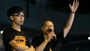  Student leader Joshua Wong (L) listens as Occupy Central leader Benny Tai speaks during the evening session at a pro-democracy protest site outside the central government offices in Hong Kong October 19, 2014 in Hong Kong.