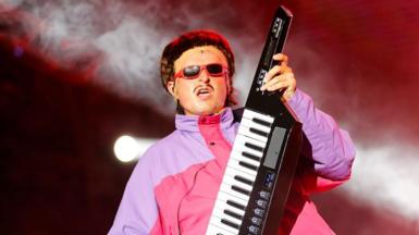 Oliver Tree performing wearing shades and playing a keytar during the Exit Festival in Serbia in 2024
