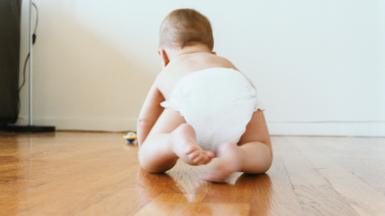 A baby crawling on a wooden floor