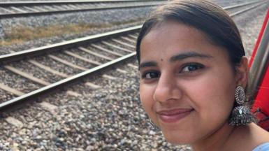 Harshita Brella stares into the camera with train tracks in the background