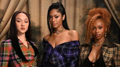 Stella Quaresma is on the left in a red and green tartan blazer. Jorja Douglas is to the middle in a black and purple tartan off-the-shoulder dress. Renee Downer is on the left in a black and green tartan jacket which she is wearing over a black top. 