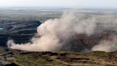 Large plumes of white smoke billow out of a large canyon in China