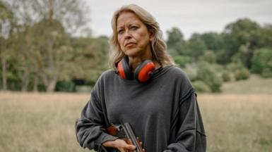Nicola Walker as Alice holding a shotgun in her hand 