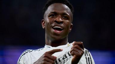 Vinicius Jr points to the Real Madrid badge