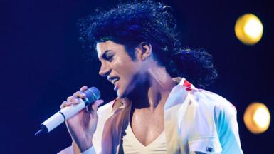Jaafar Jackson, wearing white and holding a microphone, performing as Michael Jackson in the musical biopic Michael