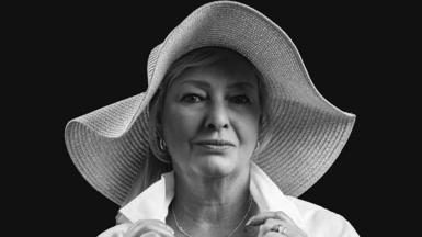 A professional black and white photo of a middle-aged woman in a wide-brimmed sunhat and a white shirt
