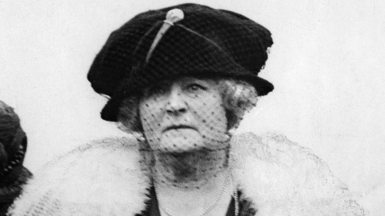 Black and white portrait of Daisy Greville, Countess of Warwick. She is wearing a large dark coloured hat with a net veil across her face and a light coloured  fur stole.