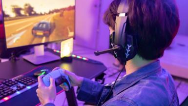 Male Gamer Playing Driving Game with Game Controller in Neon Game Room