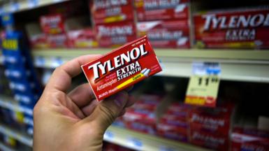 A person holds a packet of Tylenol Extra Strength