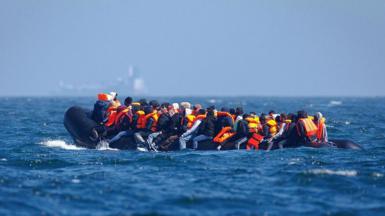 A large group of people piled onto a dingy. 