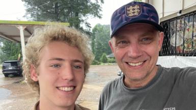 Iain Bagwell, right, is a man in his 50s. He takes a selfie with his teenage son, pictured left. Both smile for the camera.