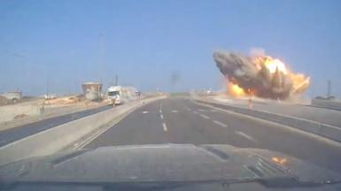A road with a large explosion happening at the side of it