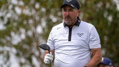 Phil Mickelson with a golf club in one hand, wearing a white shirt