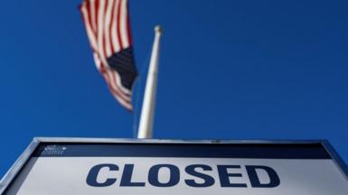 Sign saying 'CLOSED' in front of USA flag