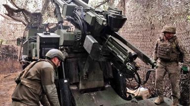 Two men load a Caesar gun near the front line in Ukraine