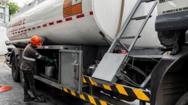 A worker prepares to fill an underground storage tank at a gas station in the Philippines.