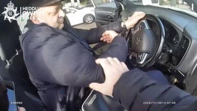 A man handcuffed in the drivers seat of a car
