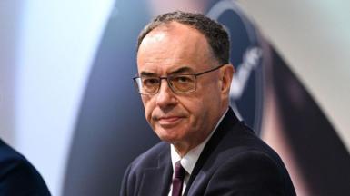 Andrew Bailey, Bank of England governor, looks straight at the camera. he's wearing glasses and a dark suit.