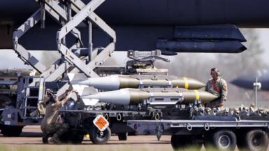 A member of the US military watches on as weapons are loaded onto an American aircraft at RAF Fairford