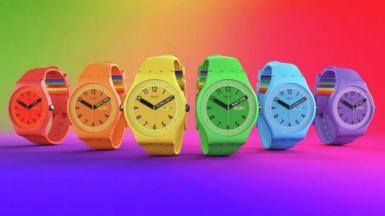 Six Swatch watches, each a bright colour. A rainbow pattern is on the strap