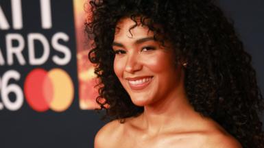 Olivia Dean smiling on the red carpet at the 2026 Brit Awards