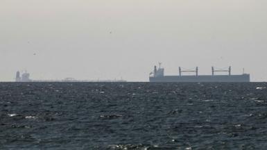 A cargo ship is seen on the horizon in the Gulf, near the Strait of Hormuz