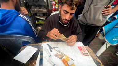 Baraa Abu al-Aoun repairing bank notes at a market in Gaza City