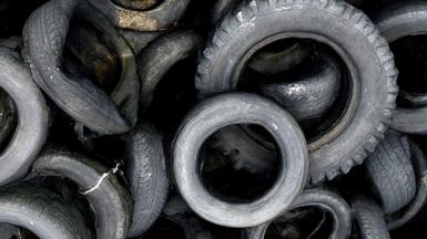 A close-up shot of a pile of different-sized old tyres laying on top of each other. 