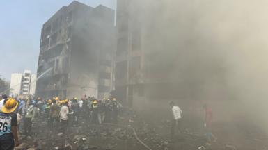 Rescue team members work as smoke rise at the crash site where an Air India plane crashed in Ahmedabad, India