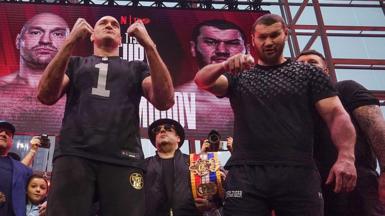 Tyson Fury puts up his fists as Arslanbek Makhmudov points to the camera