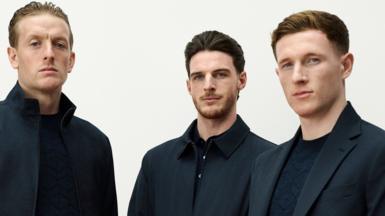 Head and upper body of three England footballers in smart dark suits coats  from Marks and Spencers
