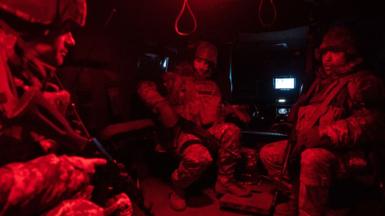 Three Ukrainian soldiers of the 425th Skala Battalion are seated in a dark room awaiting to go to the frontline