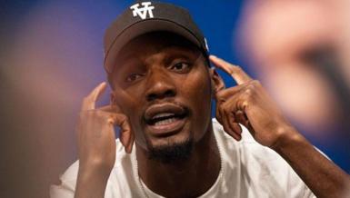 US track and field sprinter, Fred Kerley, talks with the press ahead of the Enhanced Games. He points to his face with his hands, mid-conversation.