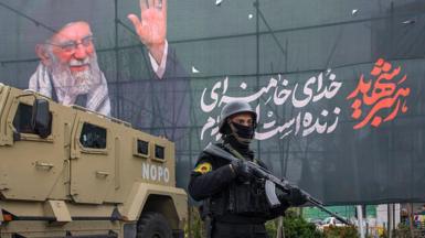 A police officer stands near an armoured-vehicle and a poster featuring the late Supreme Leader Ali Khamenei on 28 March 2026 in Tehran, Iran.