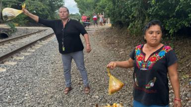 Members of Las Patronas hold out bags of food by the side of a railway track