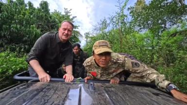 Sommerville and the young rebels on an open top vehicle driving through jungle