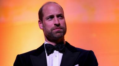 Head and shoulders picture of Prince William attending the Centrepoint Awards, standing in front of a yellow and orange background