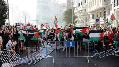 Pro-Palestinian protesters in the middle of the road next to overturned barriers
