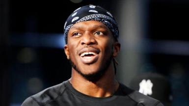  KSI smiles while wearing a black bandana and t-shirt 