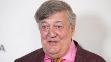 Sir Stephen Fry in a pink shirt, gold tie and maroon jacket, at the premiere of Treasure during the 2024 Tribeca Festival