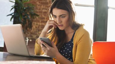 Woman on phone at laptop