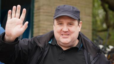 Peter Kay wears a cap and looks towards the camera