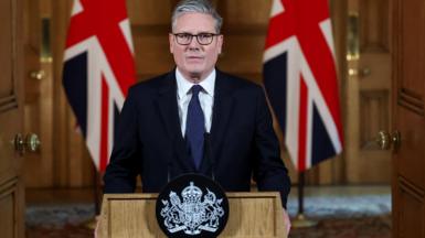 Sir Keir Starmer stands at a lectern in Downing Street flanked by two Union Jacks.