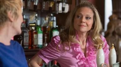 Woman in a pink top behind the bar