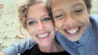 A picture of Fiona Donohoe with her son, Noah. Both are smiling at the camera. Fiona has curly, blonde hair which is tied back and Noah is wearing a blue and white checkered shirt.