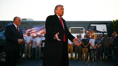 Trump speaking in front of a line of workers in front of a work truck